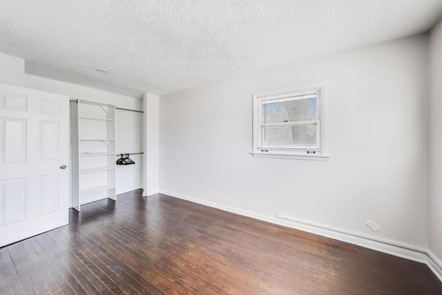 unfurnished bedroom with a closet, a textured ceiling, dark wood-type flooring, and baseboards