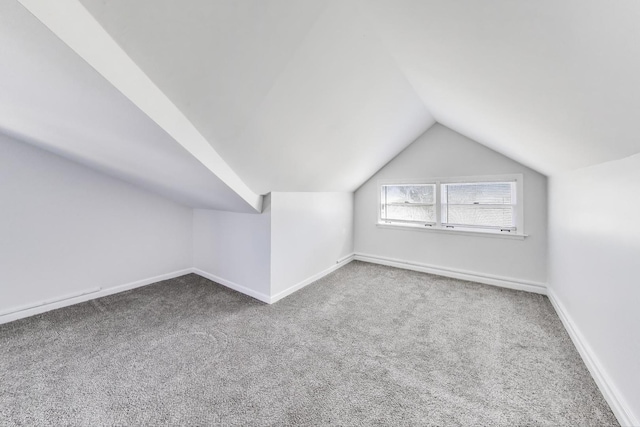 additional living space featuring baseboards, lofted ceiling, and carpet flooring