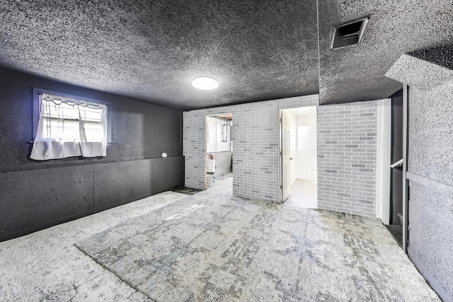 interior space with visible vents, brick wall, and a textured ceiling