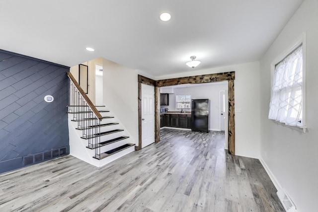 interior space featuring a barn door, stairway, wood finished floors, and visible vents