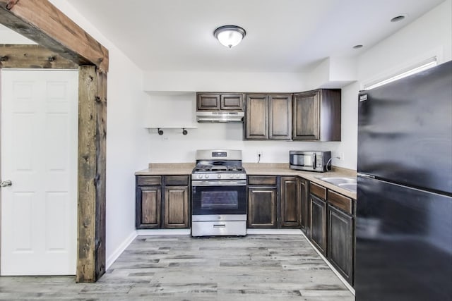 kitchen featuring under cabinet range hood, appliances with stainless steel finishes, light countertops, and dark brown cabinets