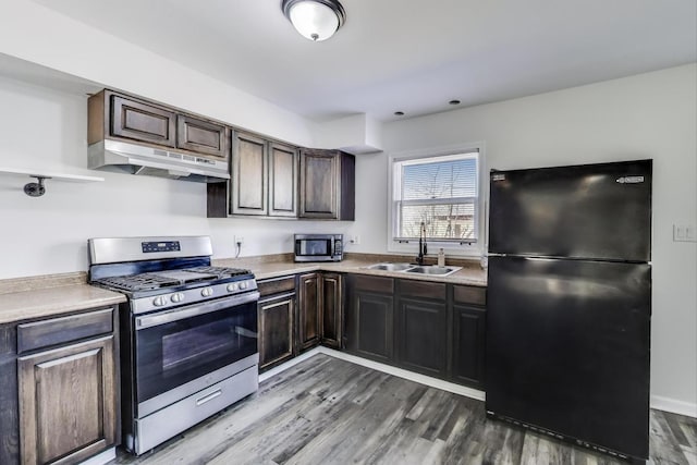 kitchen with under cabinet range hood, a sink, dark brown cabinetry, appliances with stainless steel finishes, and dark wood-style flooring