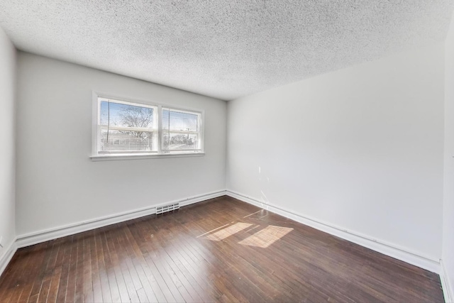 empty room with dark wood finished floors, baseboards, and a textured ceiling