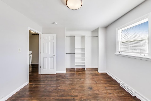 unfurnished bedroom with visible vents, wood finished floors, a closet, and baseboards