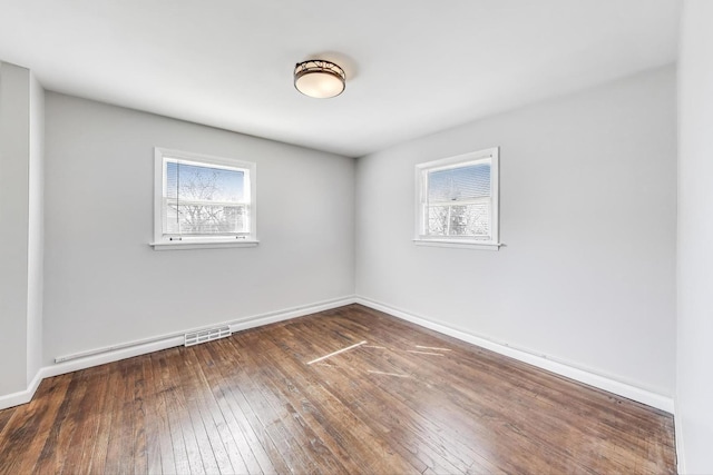 unfurnished room with hardwood / wood-style flooring, baseboards, and visible vents