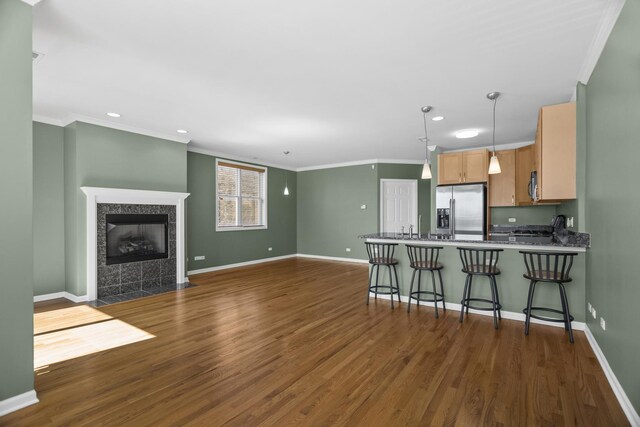 kitchen featuring a fireplace, wood finished floors, crown molding, and a sink