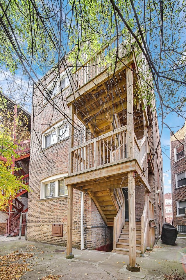 view of front of house with crawl space, brick siding, and stairs