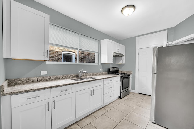 kitchen featuring light stone counters, a sink, white cabinets, under cabinet range hood, and appliances with stainless steel finishes