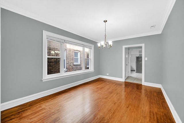 unfurnished dining area featuring wood finished floors, visible vents, baseboards, ornamental molding, and a chandelier