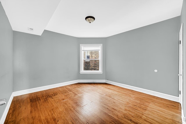 spare room featuring baseboards and wood finished floors