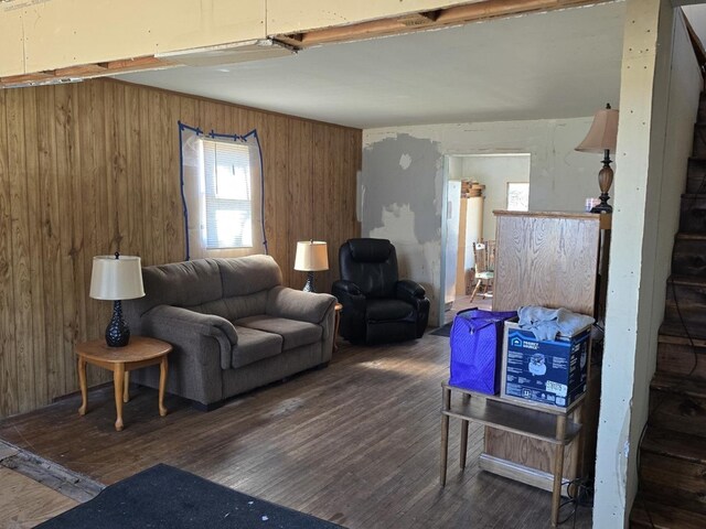 living room with wooden walls, wood finished floors, and stairs