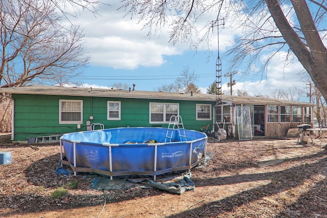 rear view of house featuring an outdoor pool and a sunroom