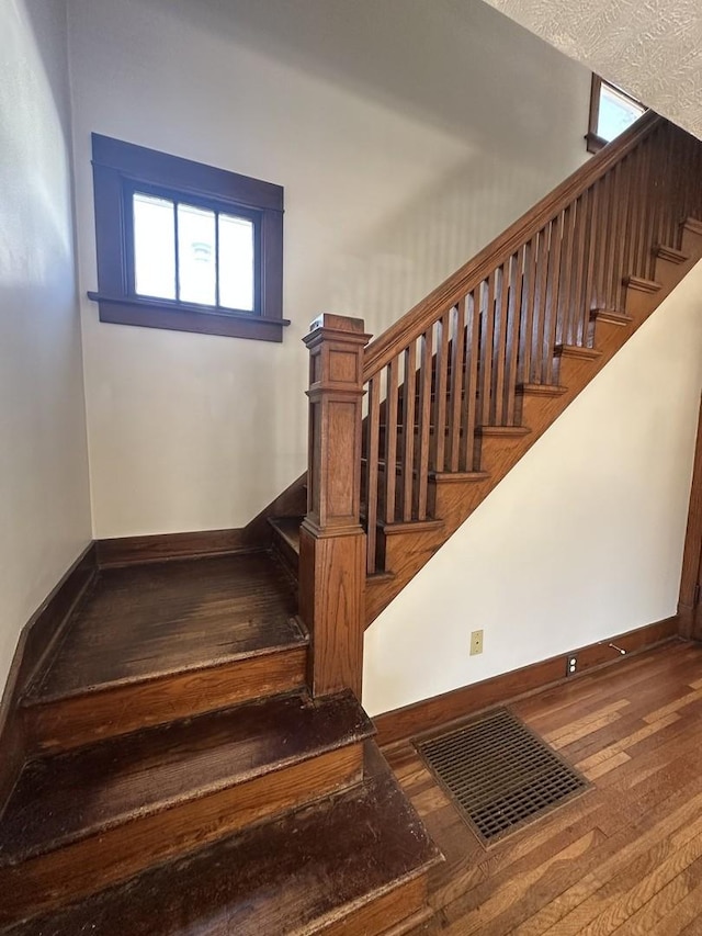 stairway featuring visible vents, baseboards, and hardwood / wood-style floors