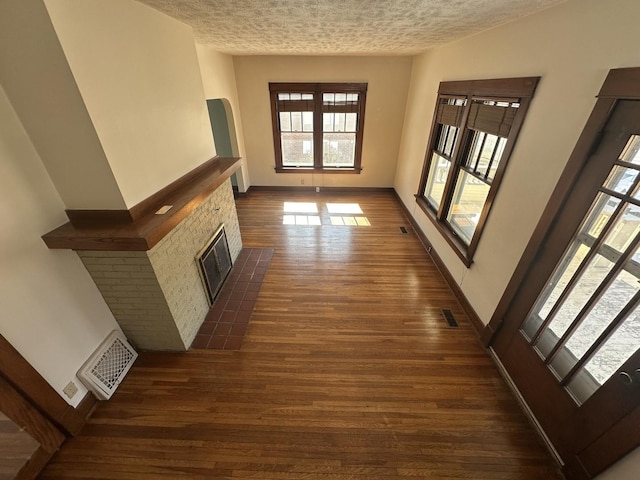 corridor with visible vents, baseboards, dark wood-type flooring, and a textured ceiling