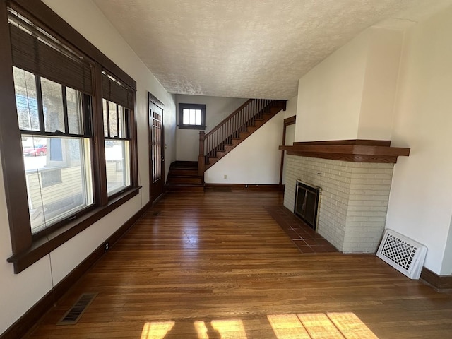 unfurnished living room featuring visible vents, a textured ceiling, and wood finished floors