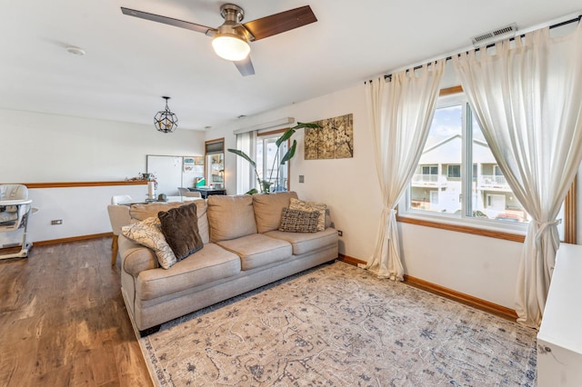 living area featuring visible vents, a ceiling fan, light wood-type flooring, and baseboards