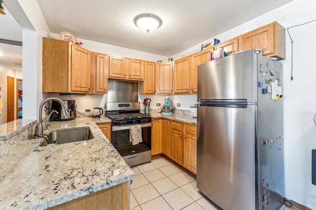 kitchen featuring a sink, light stone counters, appliances with stainless steel finishes, and light tile patterned floors