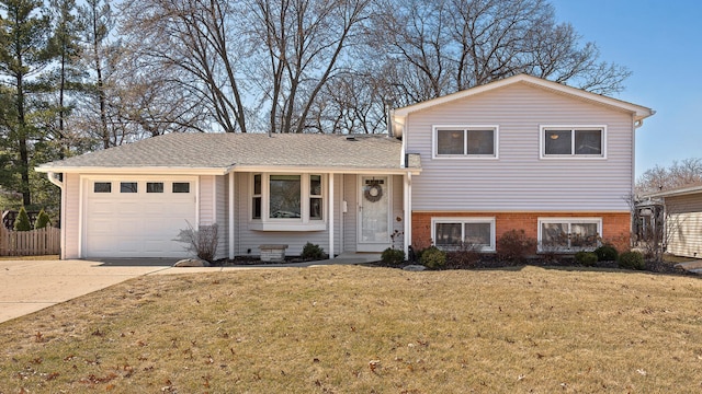 split level home featuring a front yard, fence, driveway, a garage, and brick siding