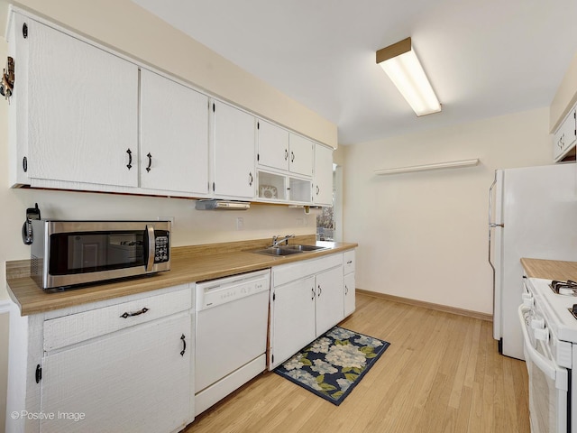 kitchen featuring white appliances, light wood finished floors, a sink, light countertops, and white cabinetry