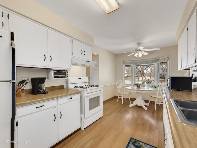 kitchen with light wood-type flooring, under cabinet range hood, white appliances, white cabinets, and light countertops