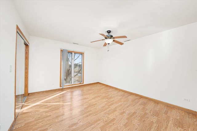 empty room featuring light wood-style flooring, visible vents, baseboards, and ceiling fan