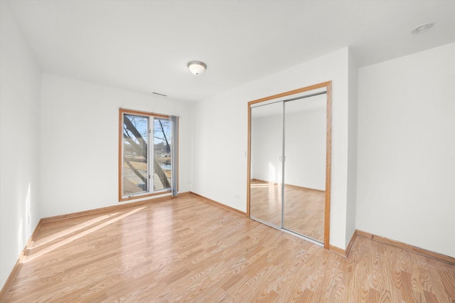 unfurnished bedroom with light wood-type flooring, baseboards, and a closet