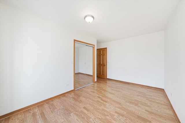 spare room featuring baseboards and light wood finished floors