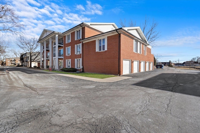 view of side of home featuring community garages and brick siding