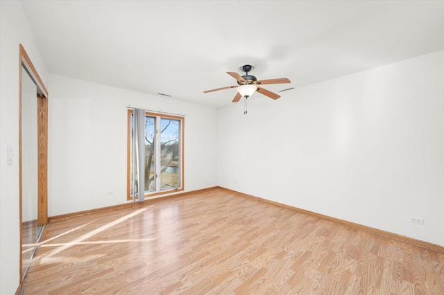 spare room featuring light wood-style flooring, baseboards, and ceiling fan