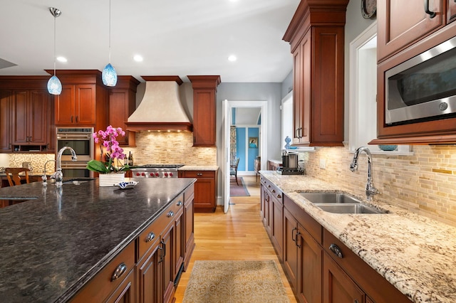 2855 Sheridan Pl, Evanston, IL 60201 - kitchen featuring stainless steel appliances, premium range hood, backsplash, decorative light fixtures, and light wood-style flooring