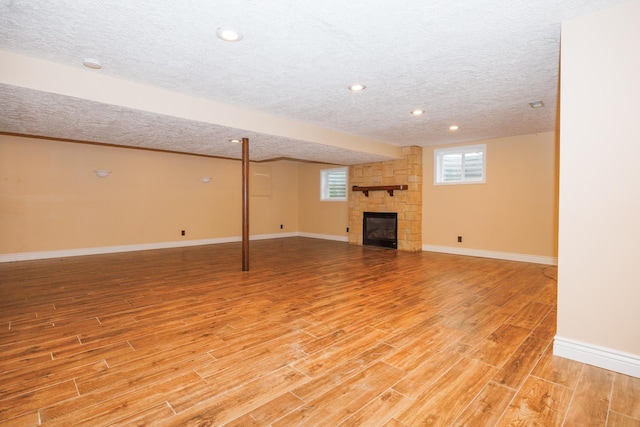 1208 Broad Creek Rd, Bloomington, IL 61704 - below grade area with a textured ceiling, light wood finished floors, baseboards, a fireplace, and recessed lighting
