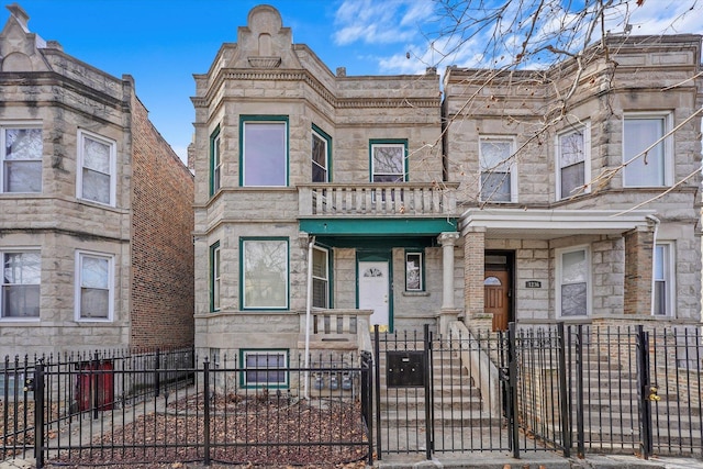 townhome / multi-family property with a balcony, a gate, and a fenced front yard