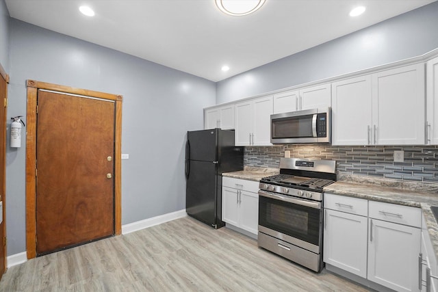 kitchen with baseboards, light wood-style flooring, white cabinets, appliances with stainless steel finishes, and tasteful backsplash