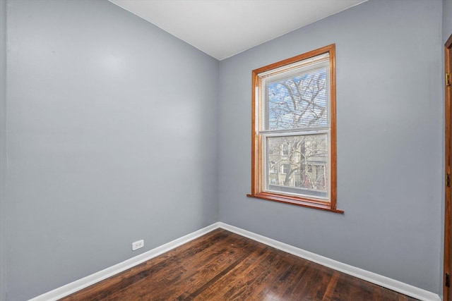 unfurnished room featuring baseboards and dark wood-style flooring