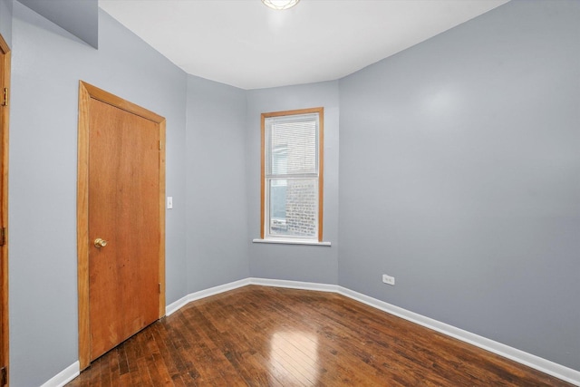 spare room with baseboards and wood-type flooring