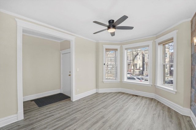 unfurnished room with crown molding, wood finished floors, and baseboards