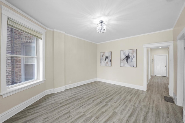 empty room with crown molding, wood finished floors, and visible vents