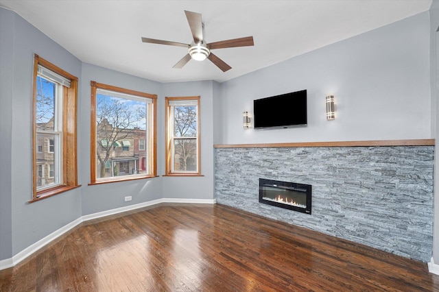 unfurnished living room with baseboards, wood-type flooring, ceiling fan, and a fireplace