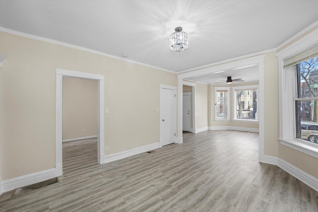 spare room featuring crown molding, wood finished floors, baseboards, and a chandelier