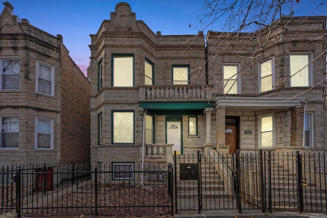 view of property featuring a balcony, a gate, covered porch, and a fenced front yard