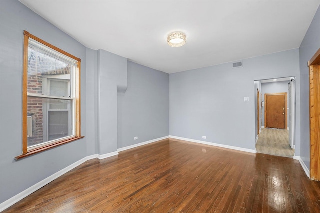 empty room featuring visible vents, wood-type flooring, and baseboards