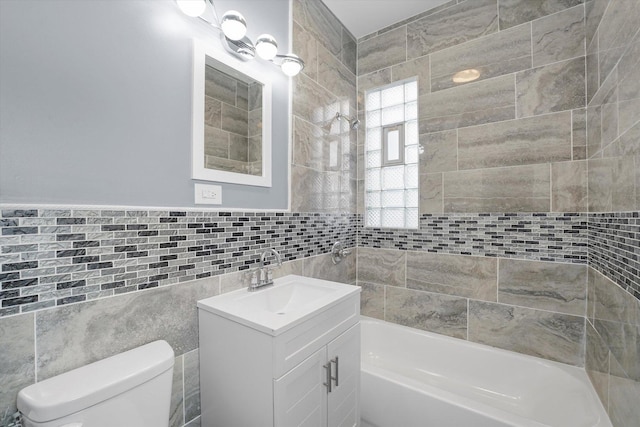 full bathroom with vanity, toilet, tile walls, and shower / bathtub combination