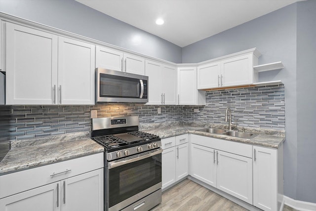 kitchen with open shelves, a sink, stainless steel appliances, white cabinets, and tasteful backsplash