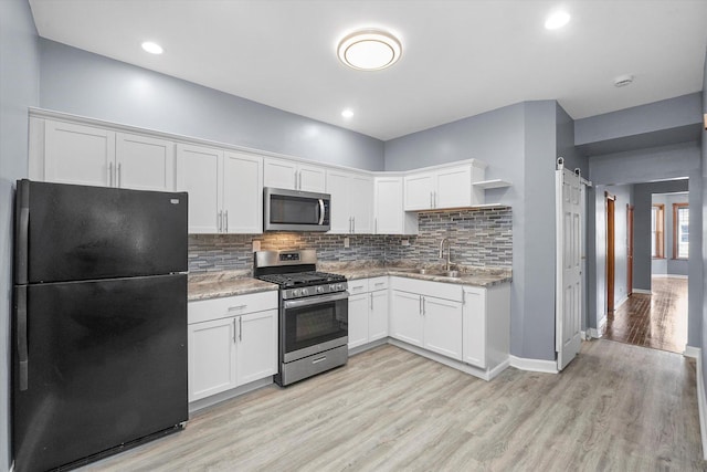 kitchen featuring a sink, a barn door, appliances with stainless steel finishes, white cabinets, and open shelves