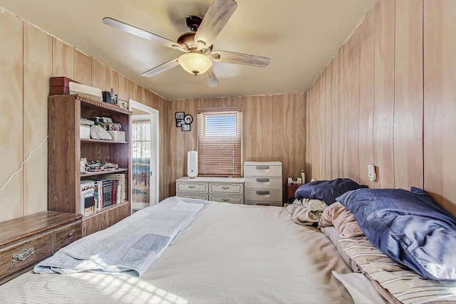 bedroom with a ceiling fan and wood walls