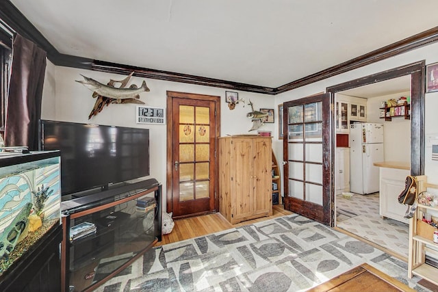 interior space featuring light wood-type flooring, french doors, and ornamental molding