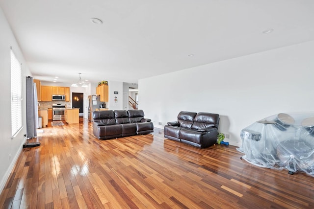2668 Bull Run Dr, Aurora, IL 60503 - living area featuring baseboards, light wood-type flooring, an inviting chandelier, and stairs