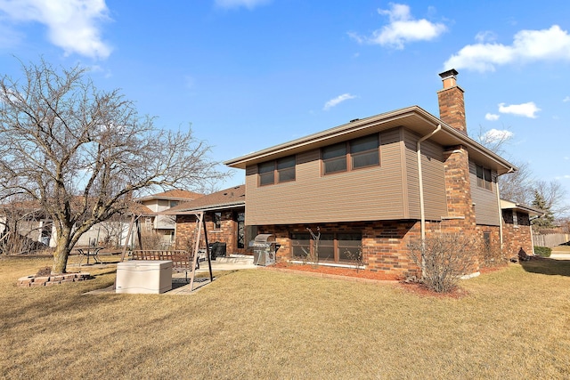 rear view of house featuring a yard, a patio area, brick siding, and a chimney