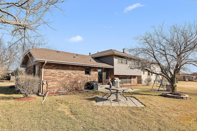 rear view of house with a patio area, brick siding, roof with shingles, and a lawn