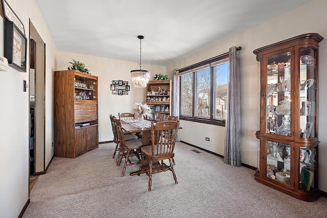 dining area featuring light carpet, visible vents, baseboards, and an inviting chandelier